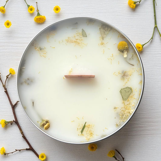 Candle in a metal container with floral elements on a light background