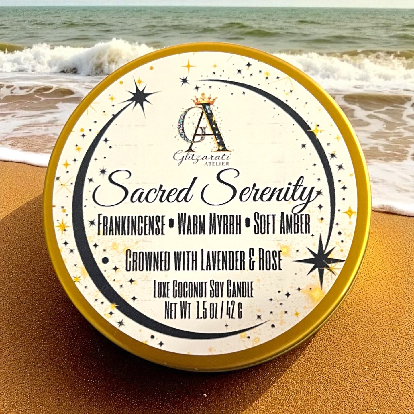 Candle tin labeled 'Sacred Serenity' on a beach with waves in the background