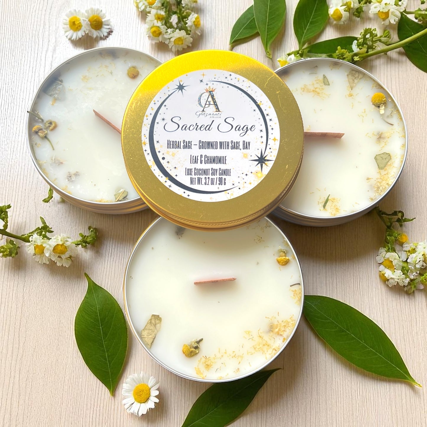 Candle with 'Sacred Sage' label surrounded by leaves and flowers on a light background