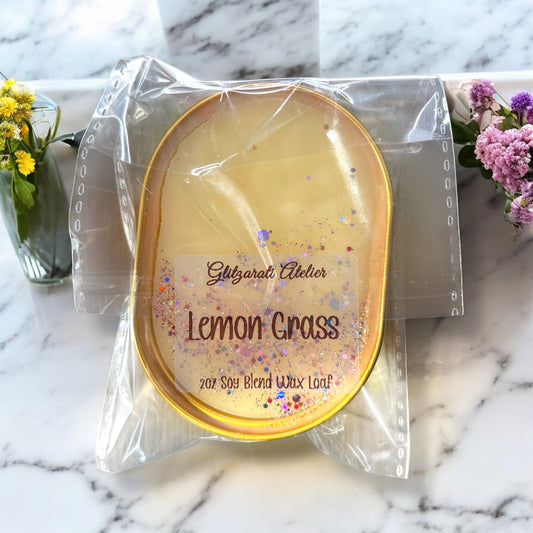 Scented wax loaf in packaging on a marble surface with flowers.