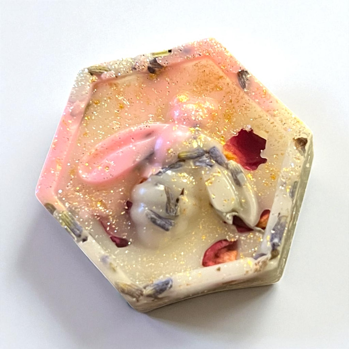 Hexagonal soap with floral and glittery elements on a white background