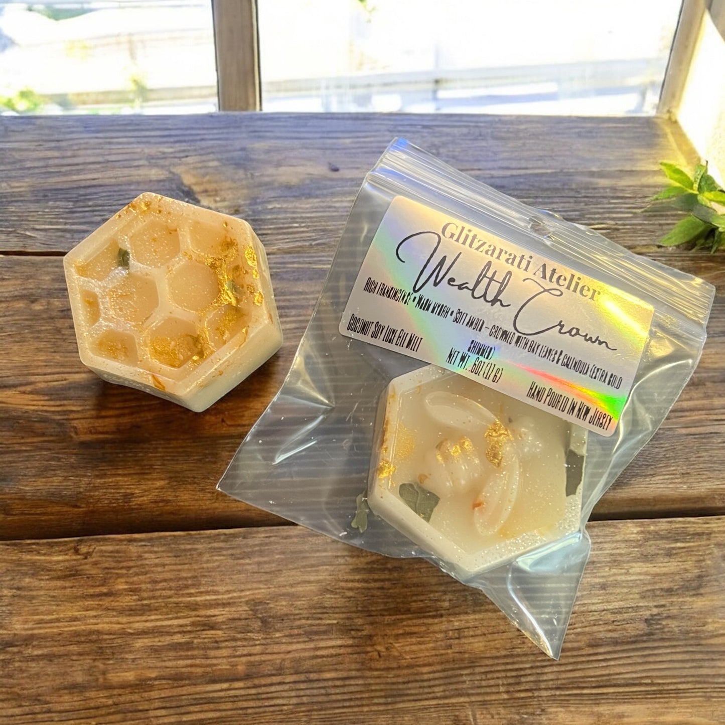 Hexagonal soap with a 'Glitzarati Atelier Wealth Crown' label on a wooden surface