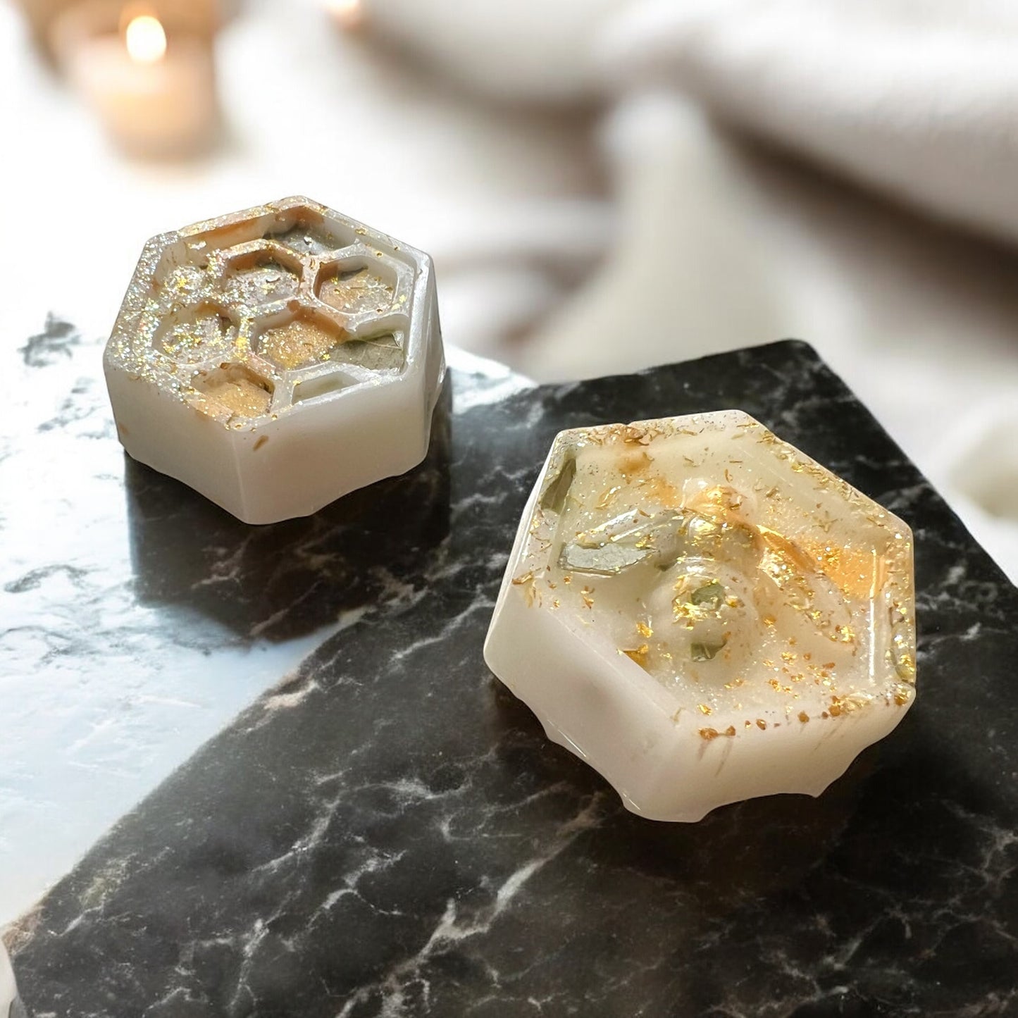 Hexagonal soap bars with embedded stones on a dark marble surface