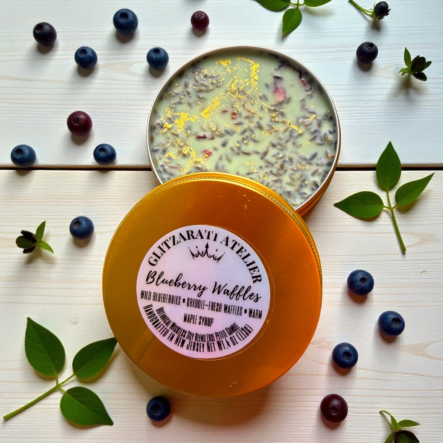 Container of Ghizlanati Atelier Blueberry Waffles with blueberries and leaves on a wooden surface