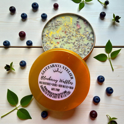Container of Ghizlanati Atelier Blueberry Waffles with blueberries and leaves on a wooden surface