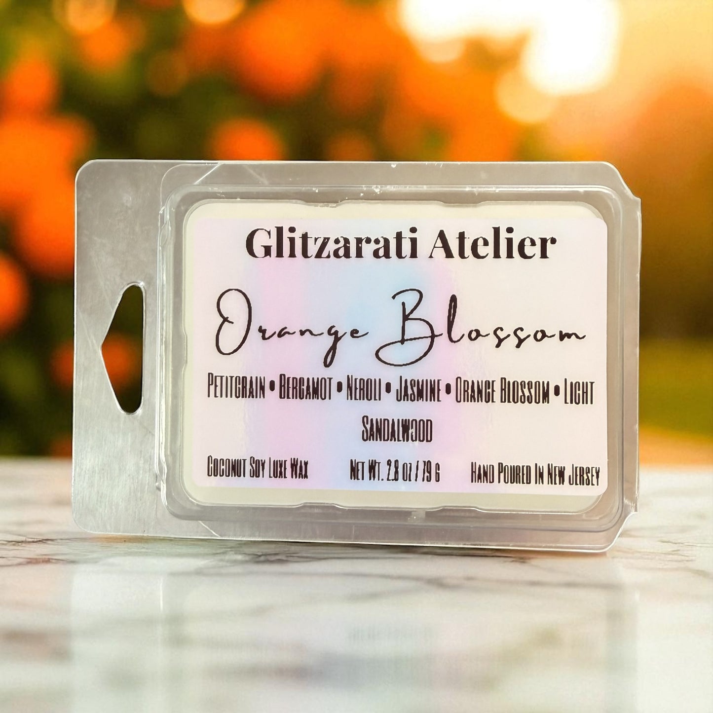 Wax melt package with 'Glitzerati Atelier' branding and 'Orange Blossom' scent on a blurred background.