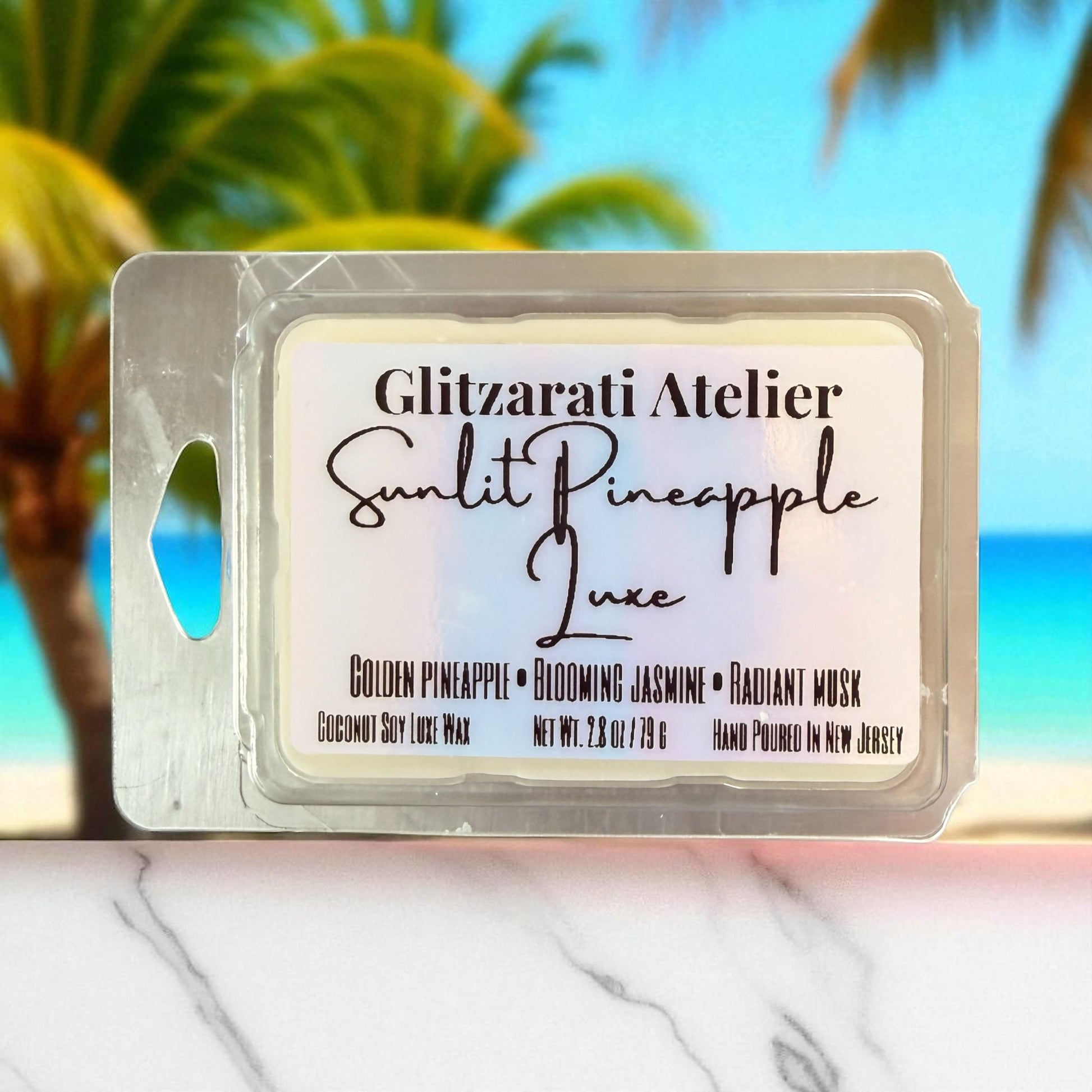 Wax melt package with 'Glitzerati Atelier' branding against a blurred beach background