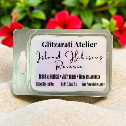 Wax melt package with 'Glitzarati Atelier' branding on a sandy background with flowers.