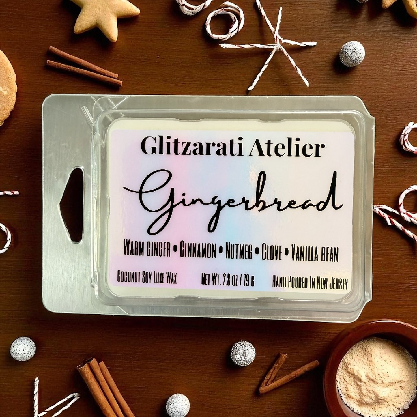 Gingerbread wax melt packaging with branding on a wooden surface with holiday decorations.