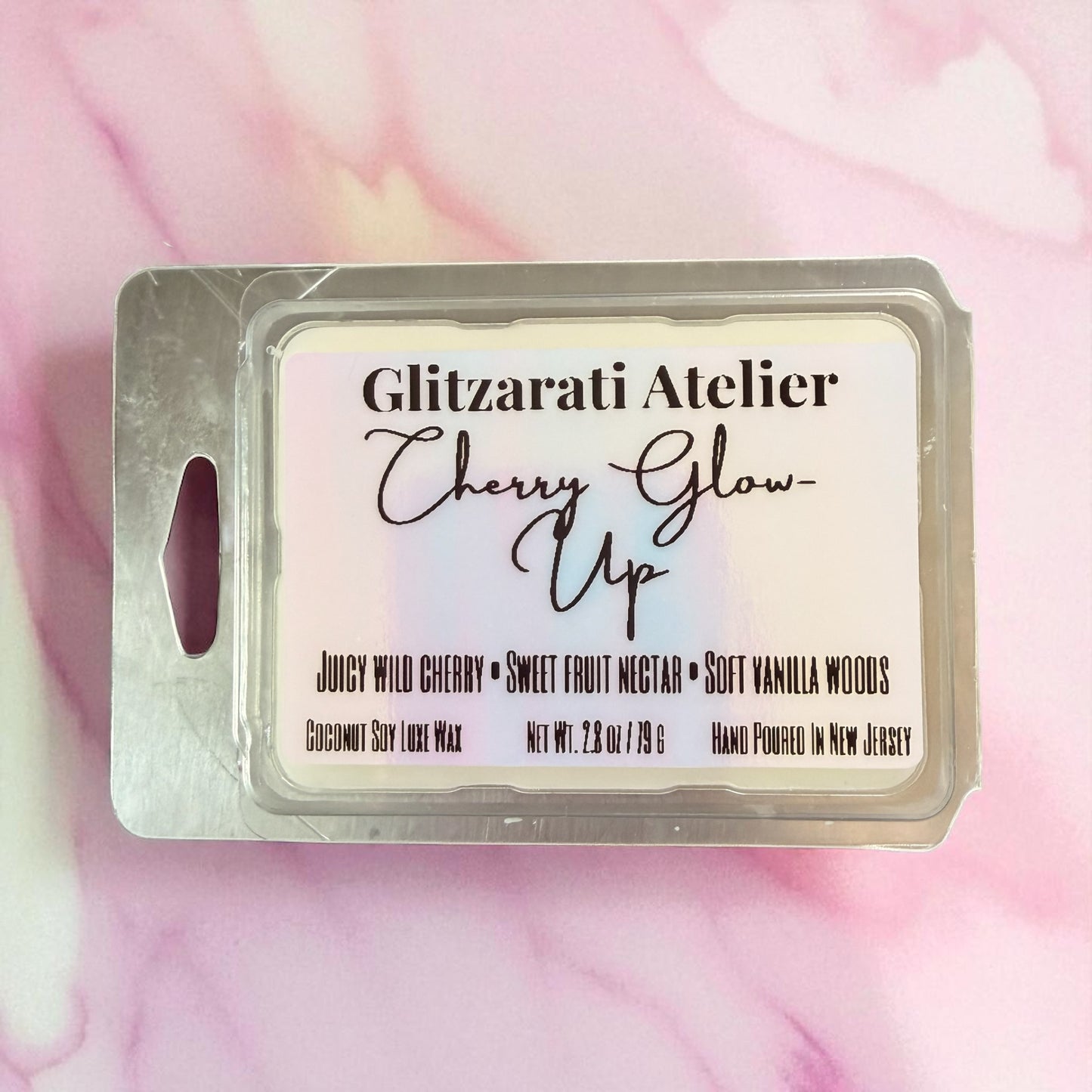 Wax melt package labeled 'Cherry Glow Up' by Glitzerati Atelier on a pink and white marbled background.