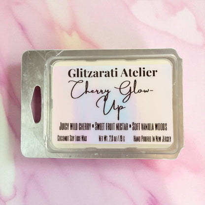Wax melt package labeled 'Cherry Glow Up' by Glitzerati Atelier on a pink and white marbled background.