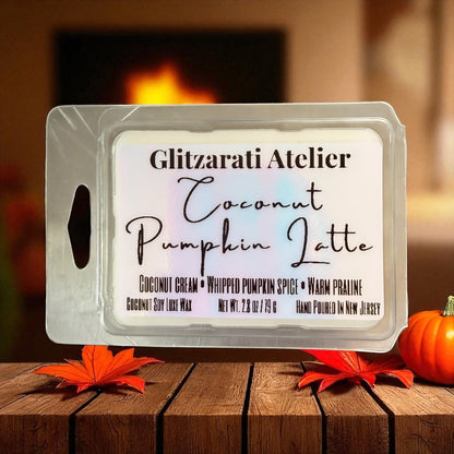 Wax melt container labeled 'Coconut Pumpkin Latte' by Glitzarati Atelier on a wooden surface with pumpkins and leaves.