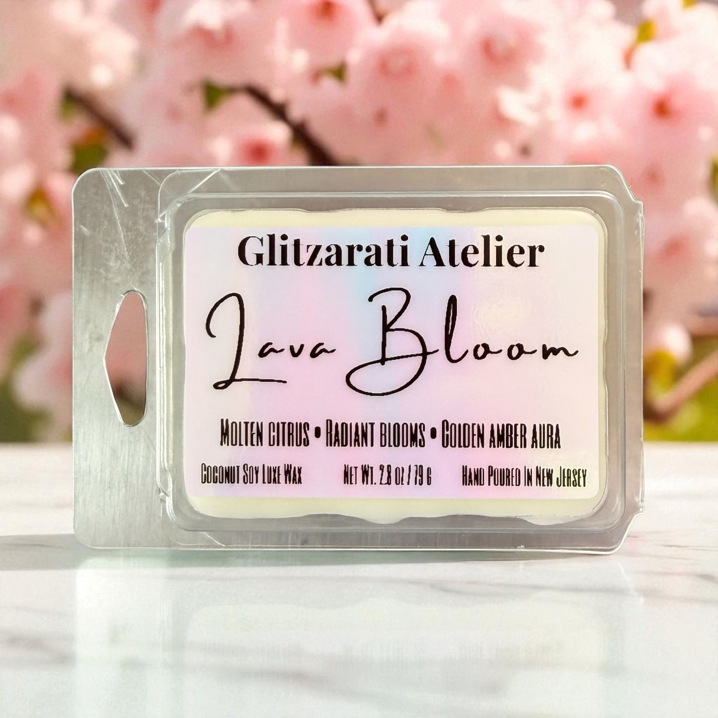 Glitzerati Atelier Lava Bloom wax melt packaging with cherry blossoms in the background