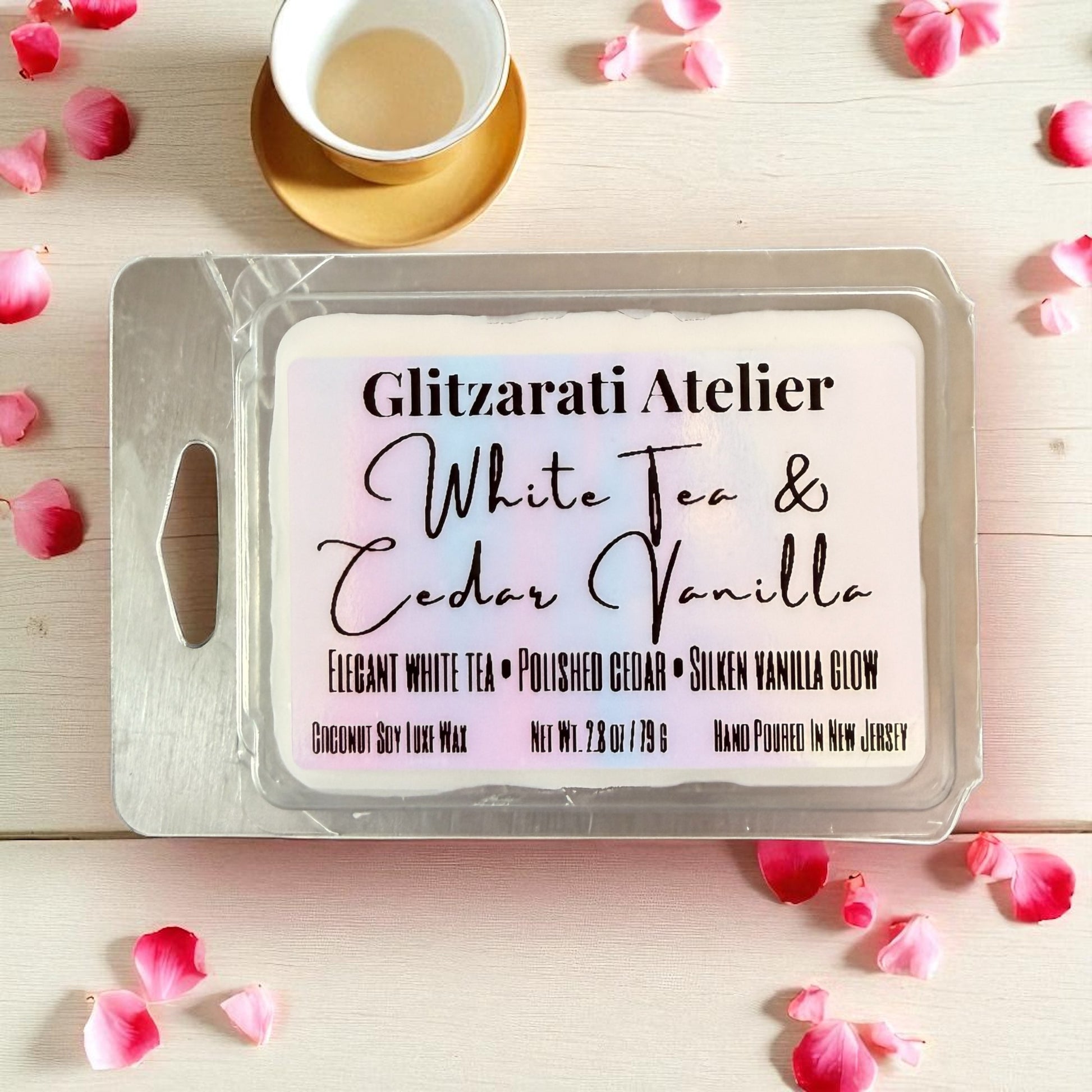 Wax melt packaging with 'Glitzerati Atelier' branding on a wooden surface with rose petals.