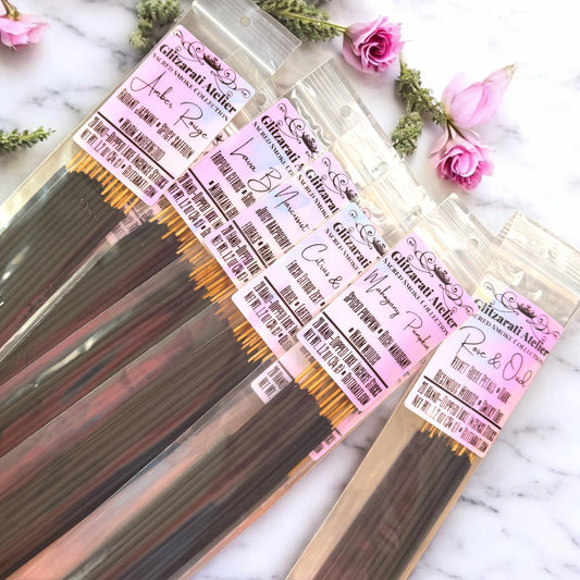 Incense sticks in clear packaging with pink labels on a marble surface with flowers.