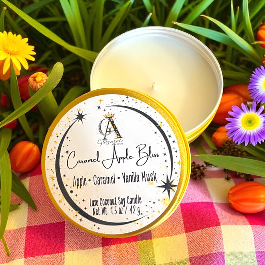Candle in a tin with a label on a checkered cloth surrounded by flowers and leaves