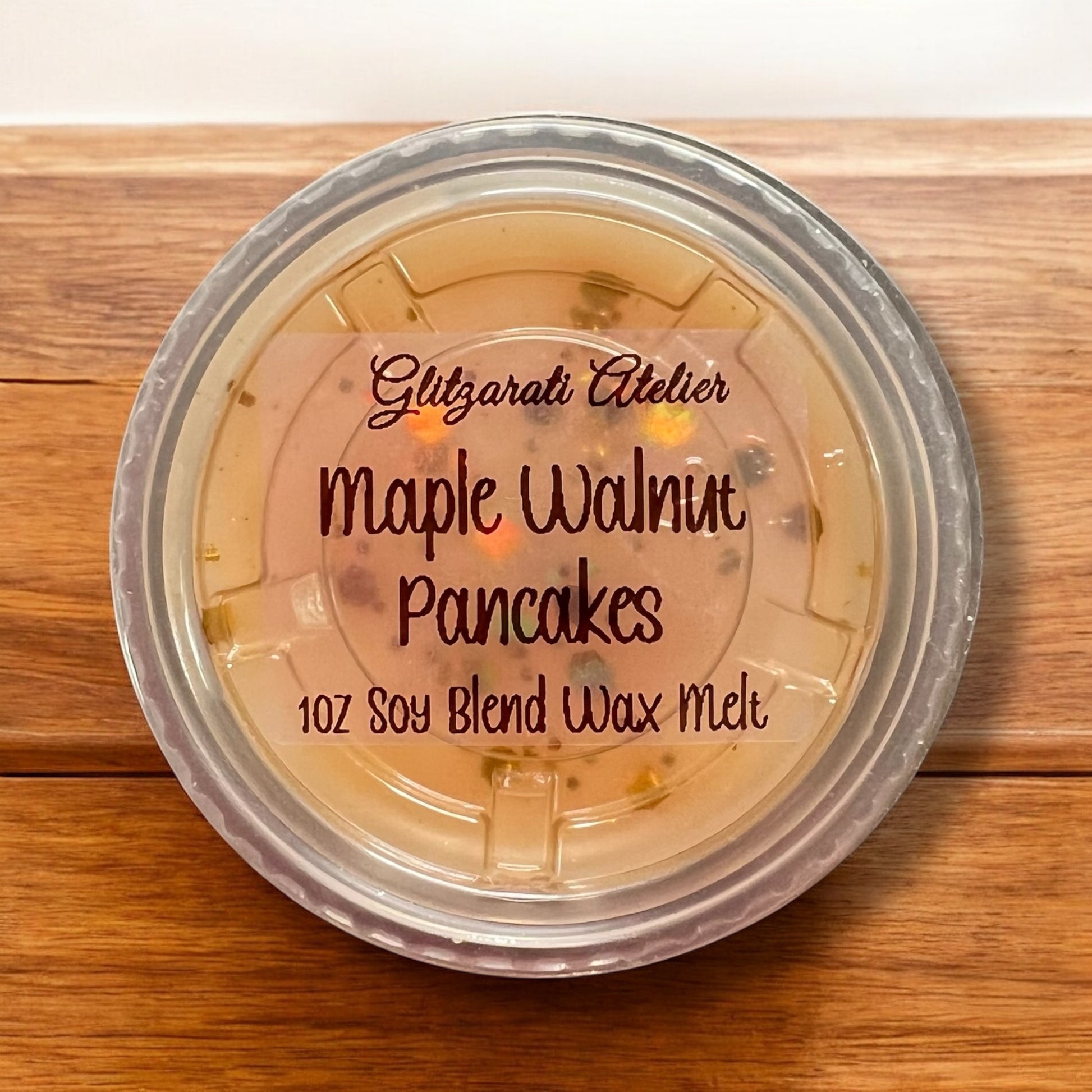 Container of Glitzarati Atelier Maple Walnut Pancakes wax melt on a wooden surface