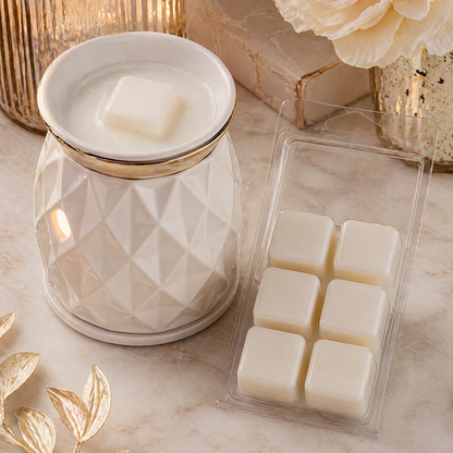 A diamond-patterned wax warmer with a candle and a pack of wax melts on a marble surface.