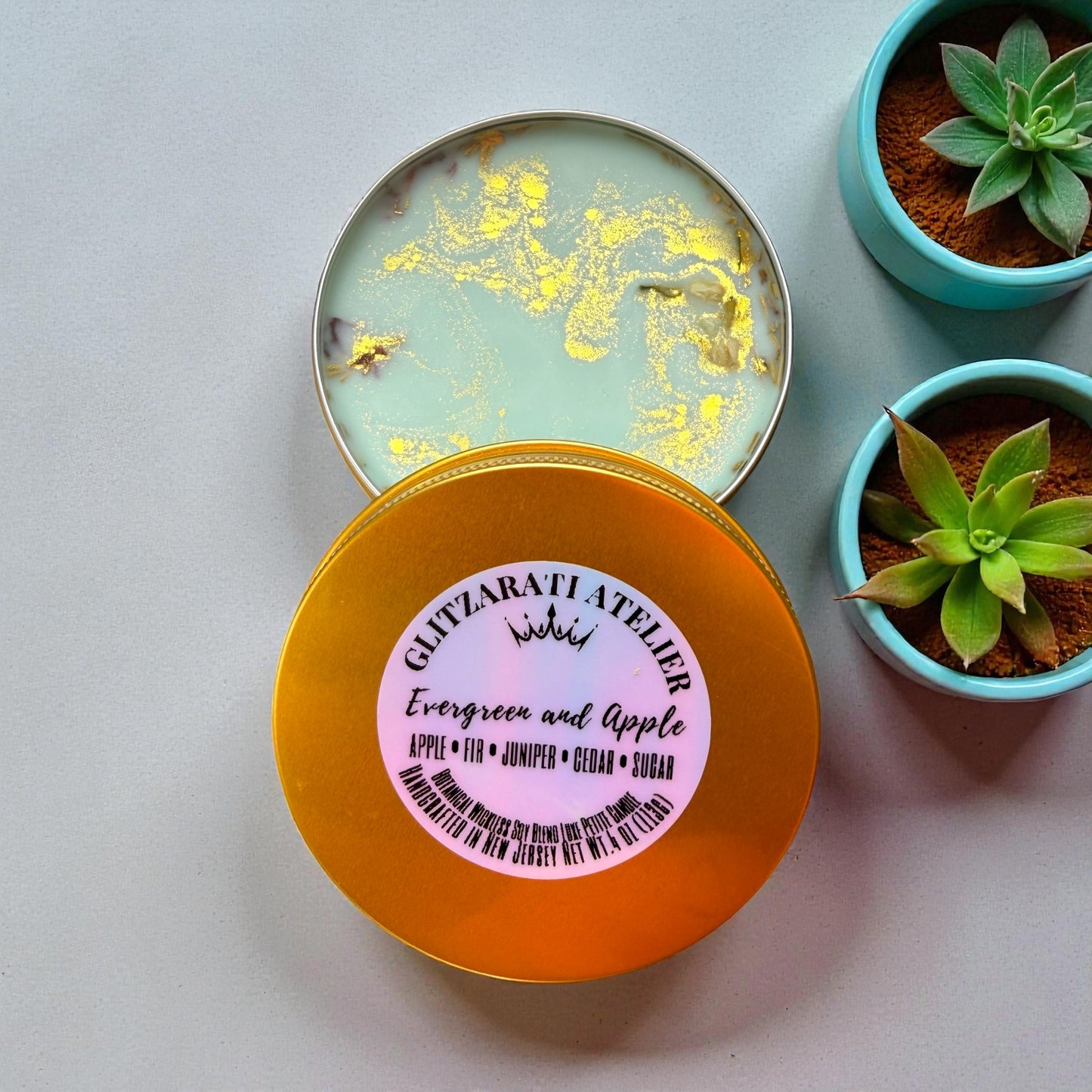 Round container with a pink label on a light gray background with potted plants.
