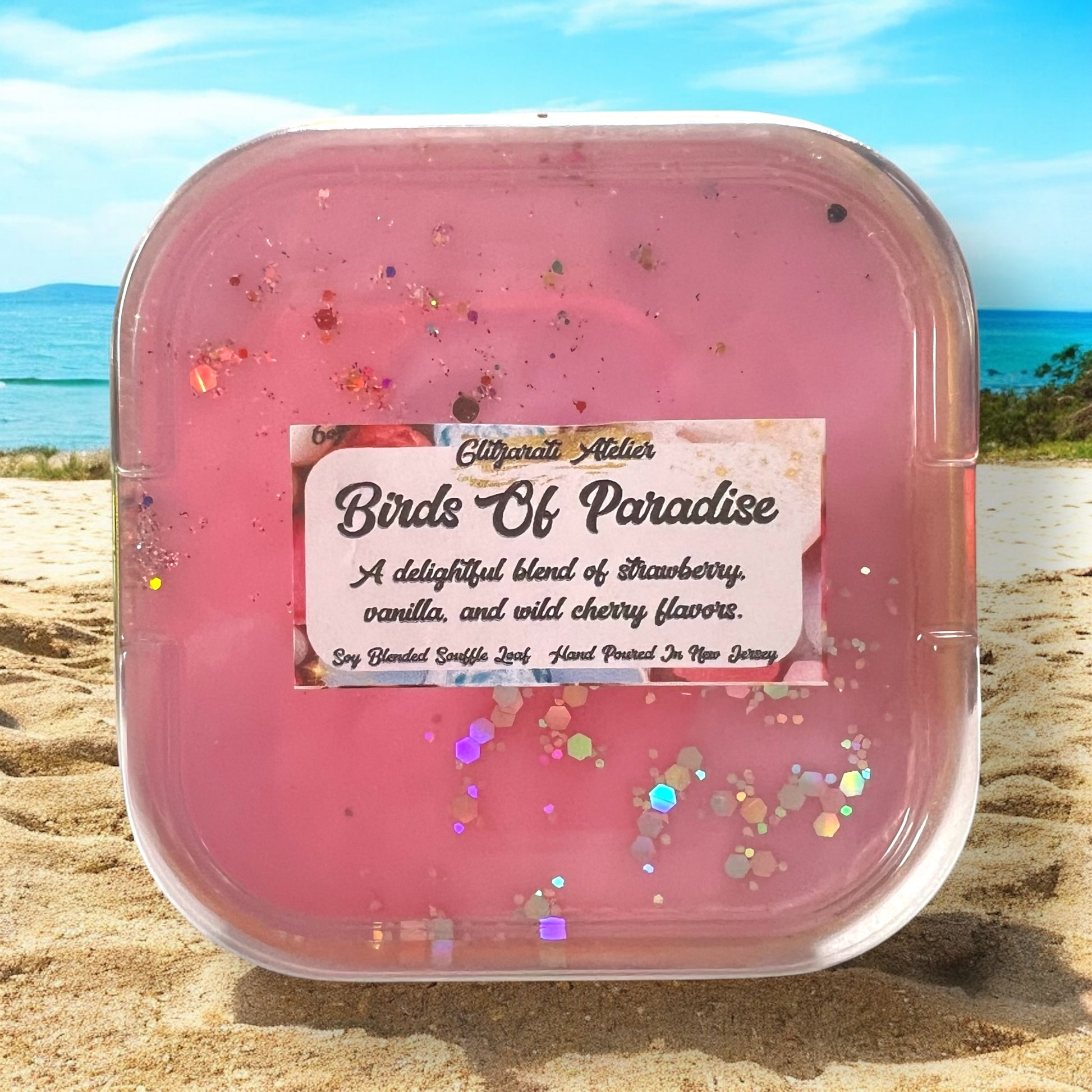 A collection of Glitzarati Atelier's scented wickless wax melt souffles in various colors, presented in aluminized tins surrounded by colorful flowers.