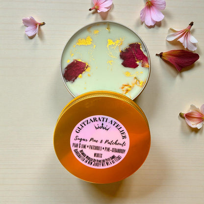 Open container of Glitzarati Atelier body scrub with decorative elements on a light background