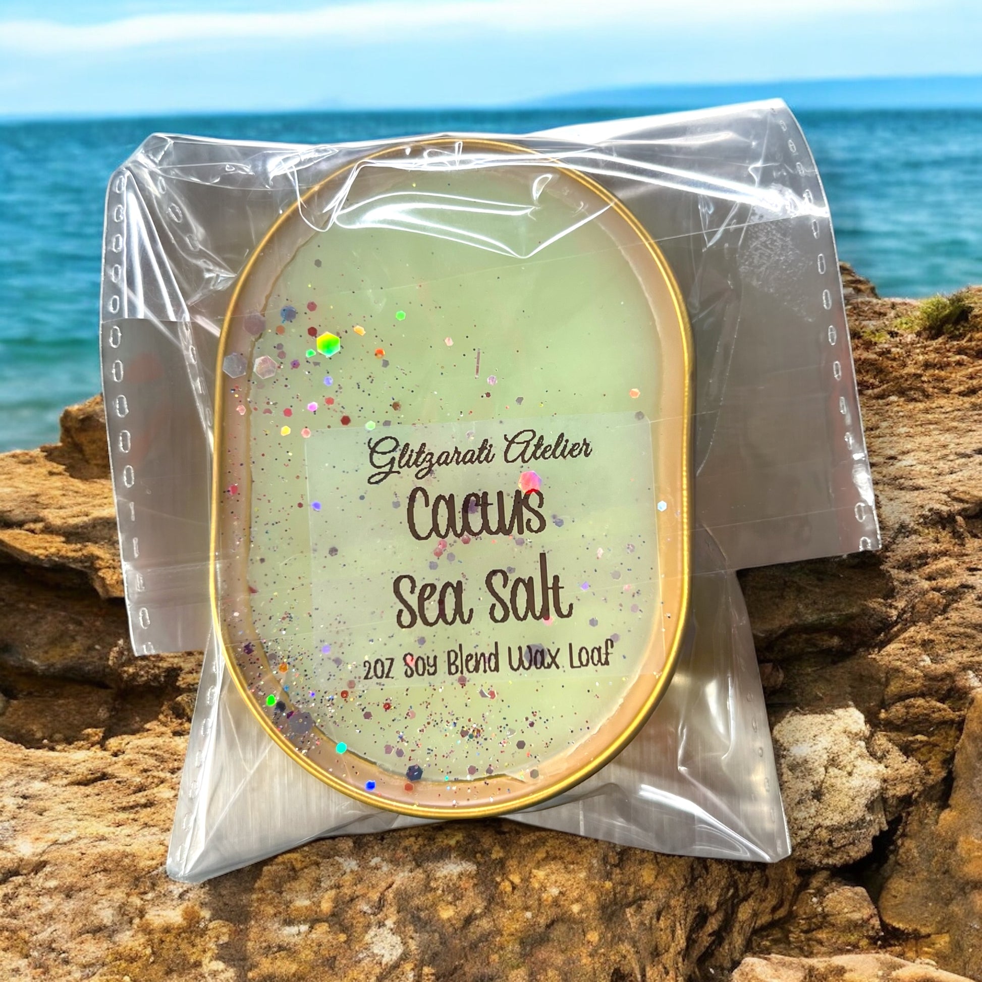 Packaged cactus sea salt candle on a rocky surface with ocean in the background