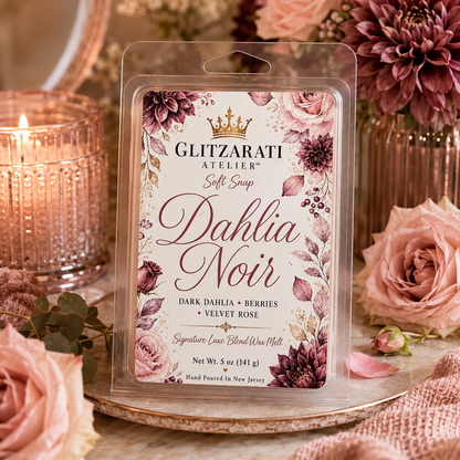 Glitzarati Atelier Dahlia Noir wax melt packaging with floral design, surrounded by roses and a candle.