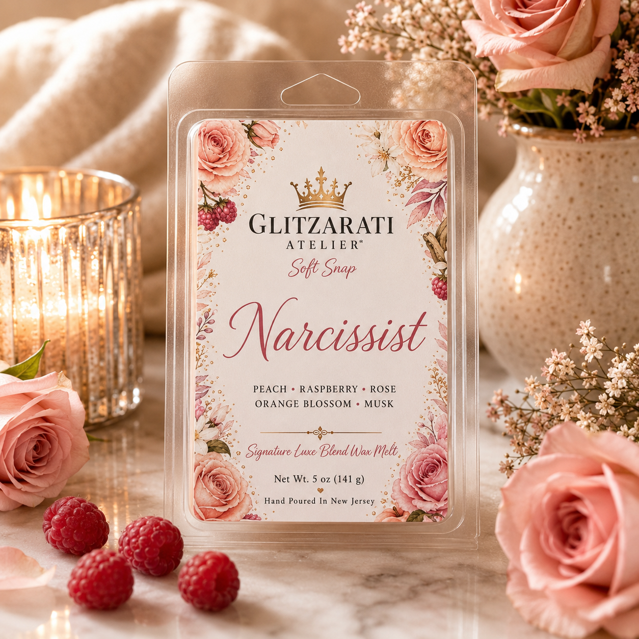 Glitzarati Atelier 'Narcissist' wax melt packaging with roses and raspberries on a marble surface.