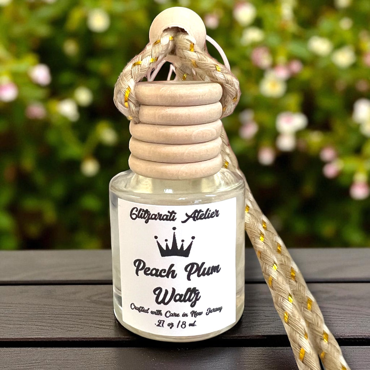 Perfume bottle with wooden cap and rope handle on a wooden surface with blurred greenery in the background