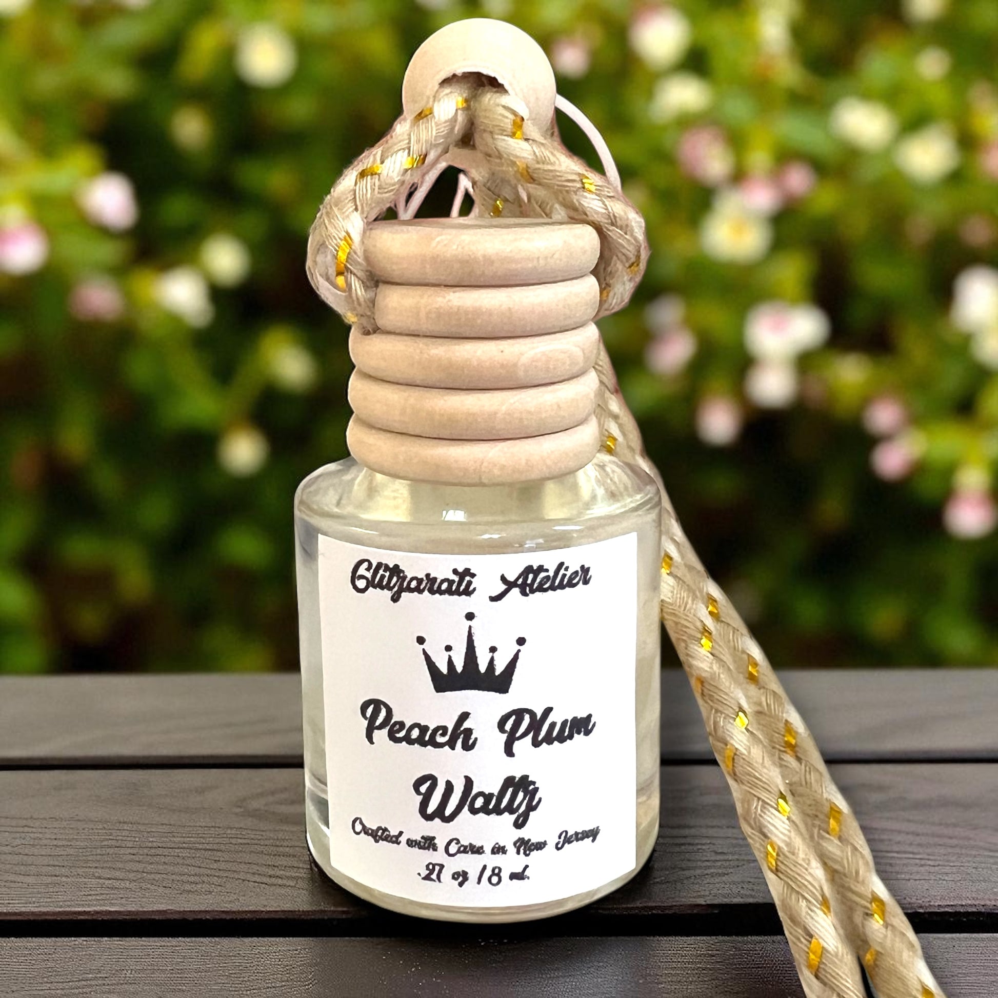 Perfume bottle with wooden cap and rope handle on a wooden surface with blurred greenery in the background