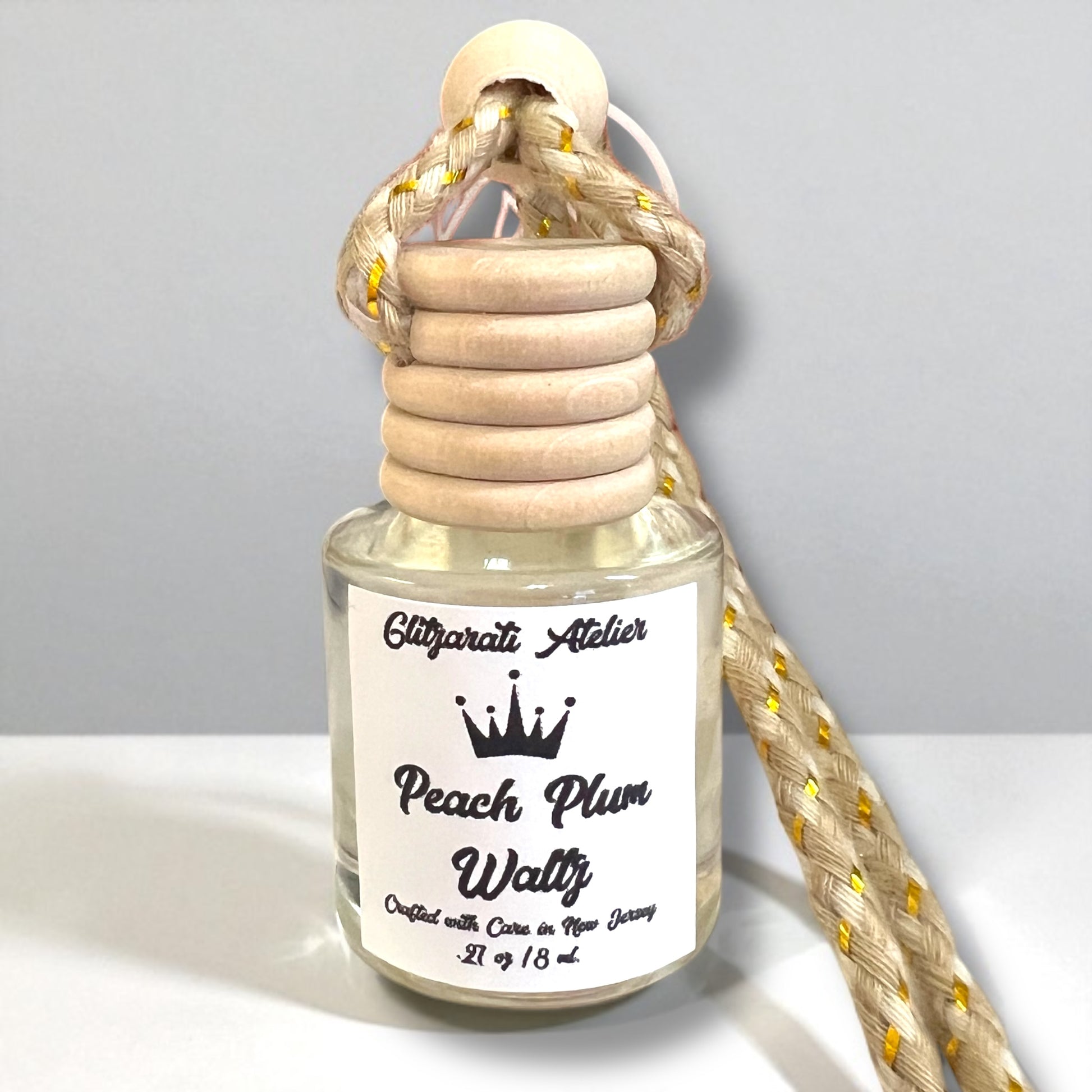 Perfume bottle labeled 'Peach Plum Waltz' with wooden cap and rope on a light gray background