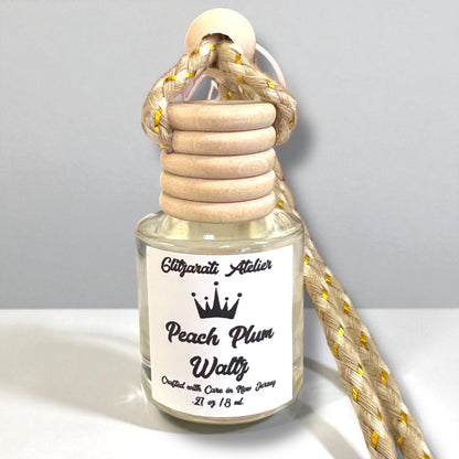 Perfume bottle labeled 'Peach Plum Waltz' with wooden cap and rope on a light gray background