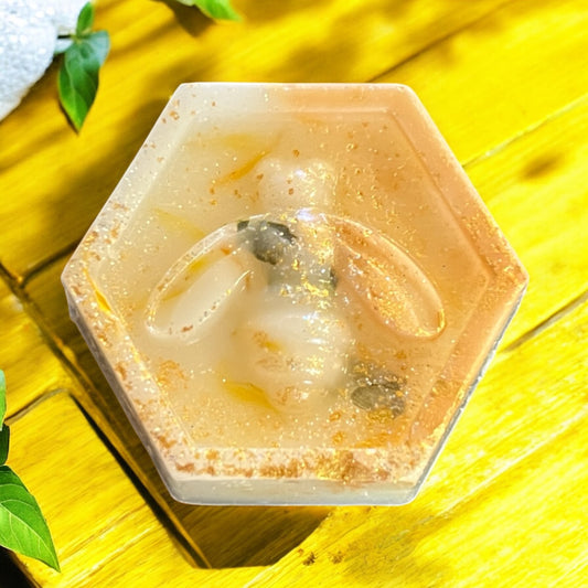 Hexagonal soap bar with a embedded object on a yellow wooden surface