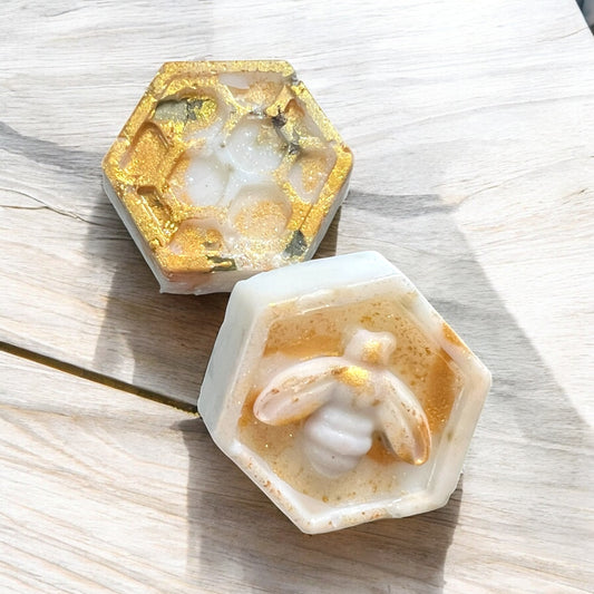 Hexagonal soap bars with gold and white design on a wooden surface