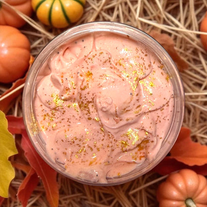 Pink slime with gold glitter in a clear container surrounded by pumpkins and leaves