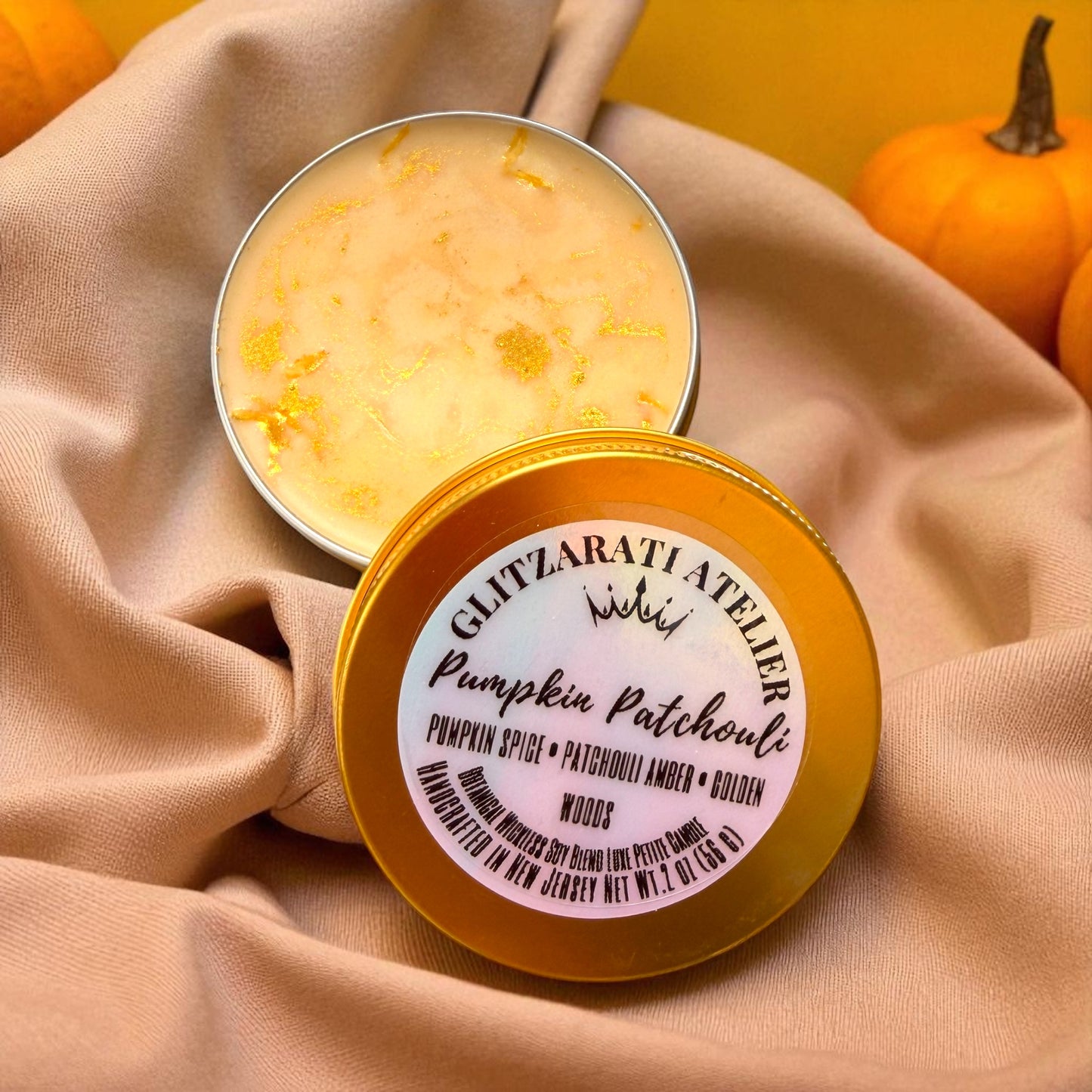 Pumpkin spice candle in a tin with a visible brand label on a beige fabric background.