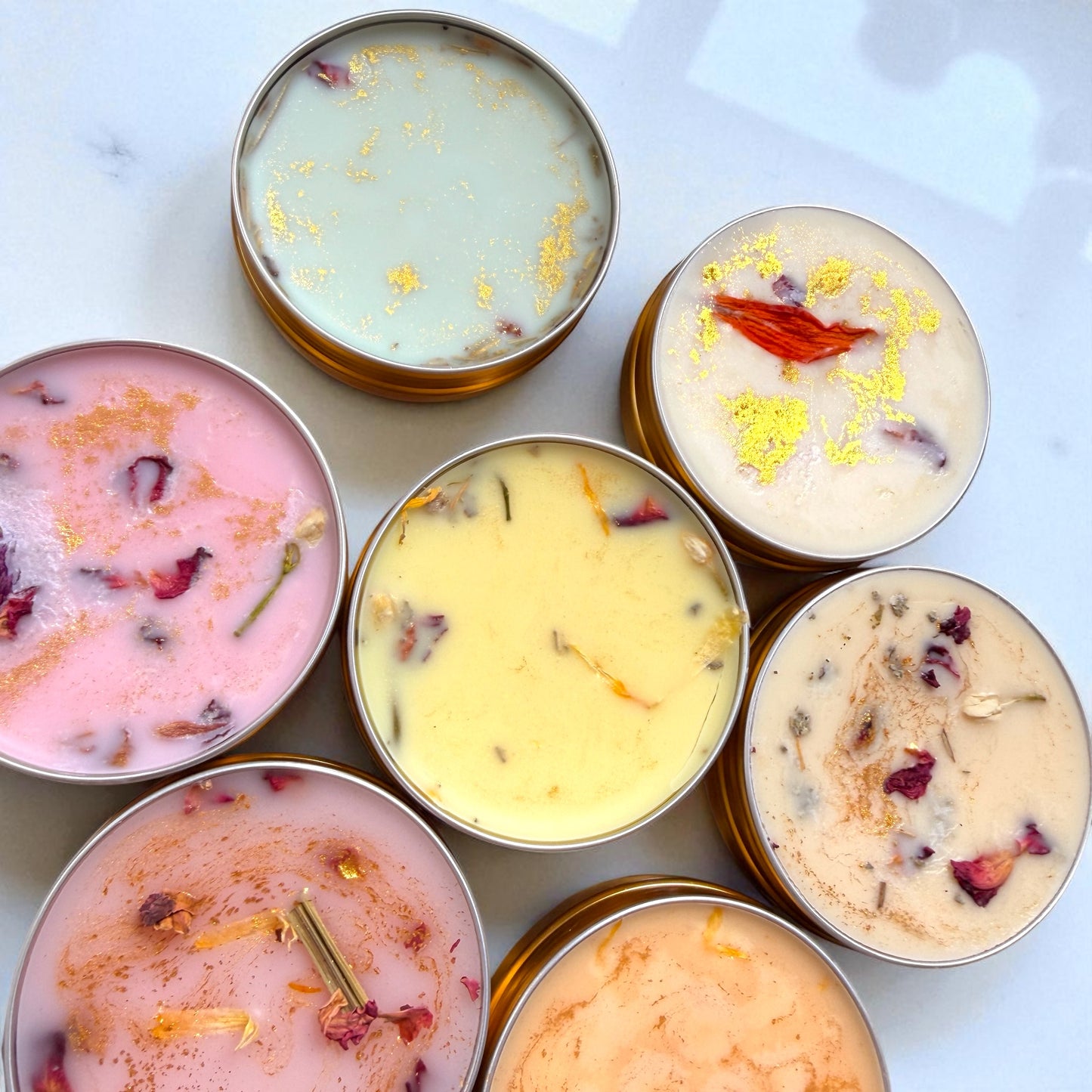 Assorted candles in tins with visible ingredients on a light background
