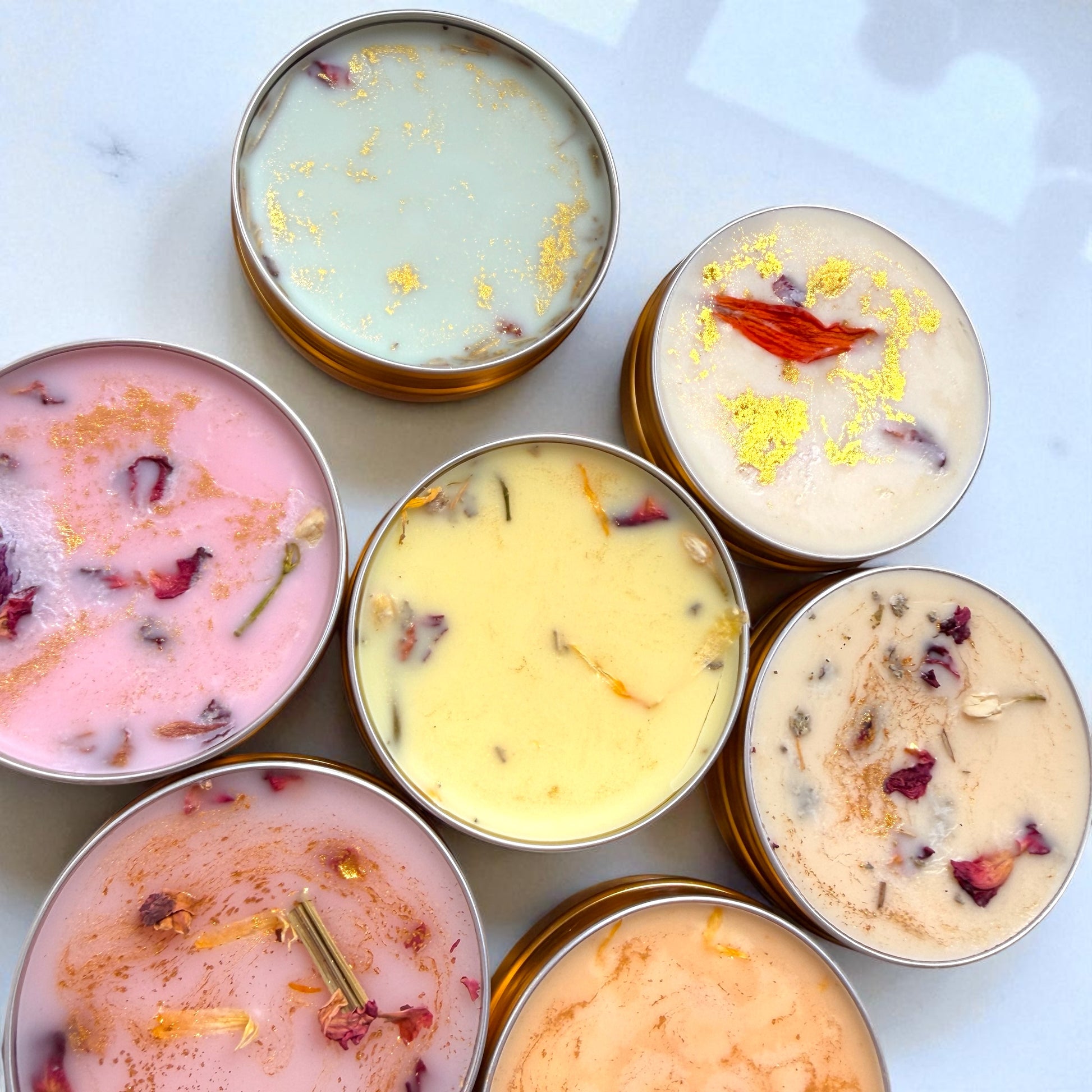 Assorted candles in tins with visible ingredients on a light background