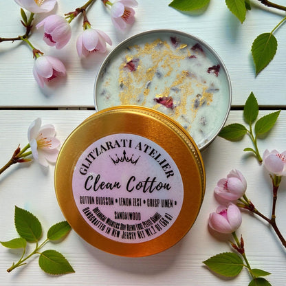 Scented candle with a decorative lid featuring cherry blossoms on a light wooden surface.