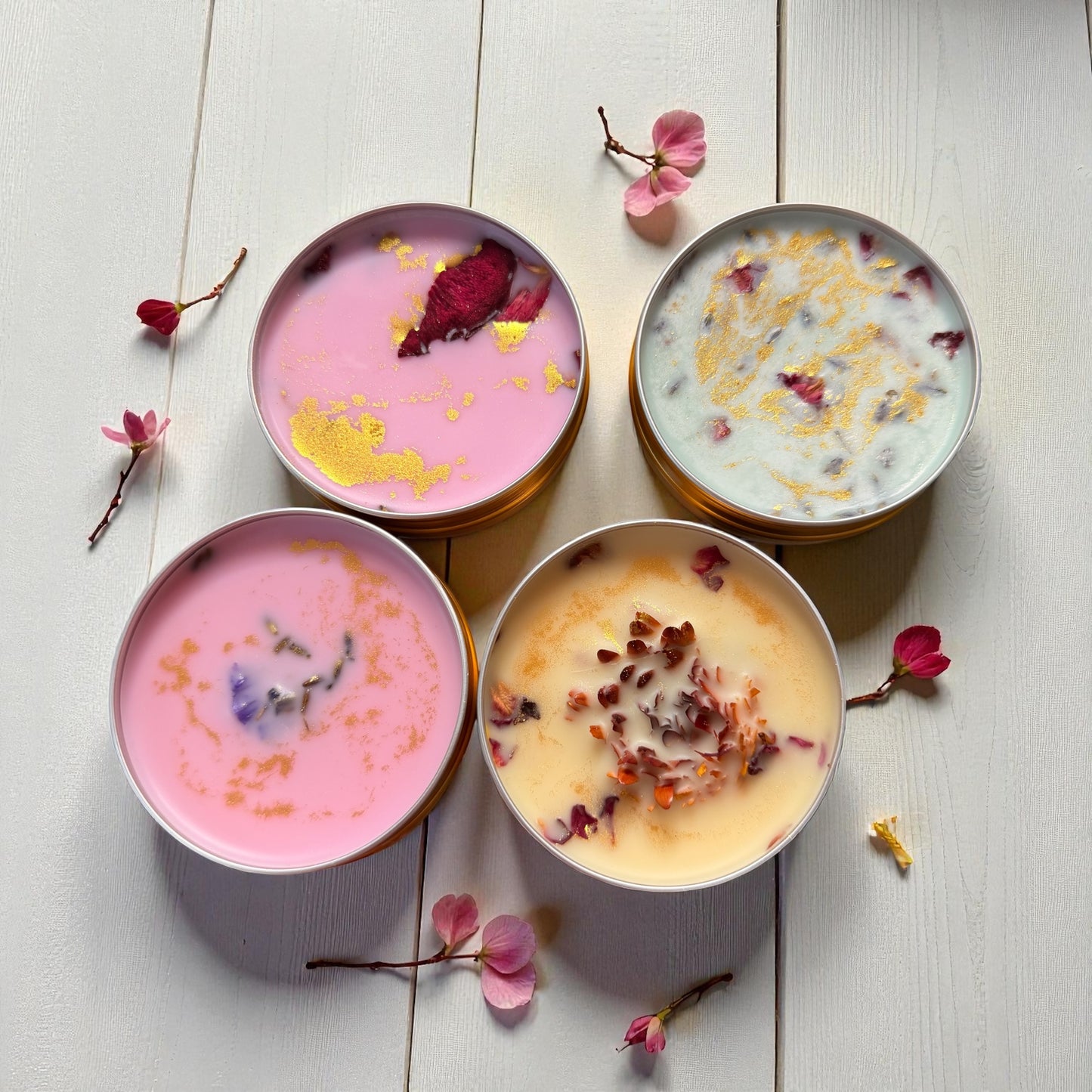 Four bowls of dessert with floral toppings on a light wooden surface.