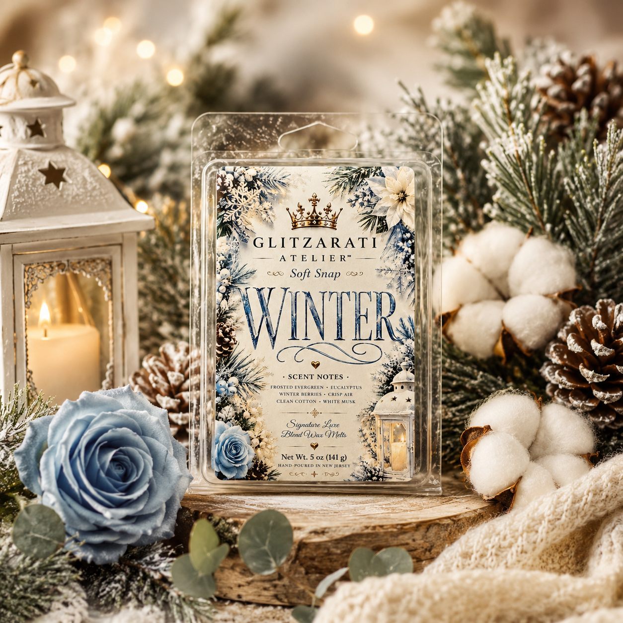 Glitzarati Atelier 'Winter' scented wax melt surrounded by winter-themed decorations including a lantern, blue roses, and pinecones.