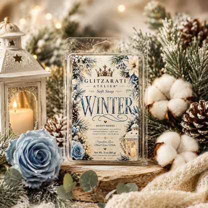 Glitzarati Atelier 'Winter' scented wax melt surrounded by winter-themed decorations including a lantern, blue roses, and pinecones.