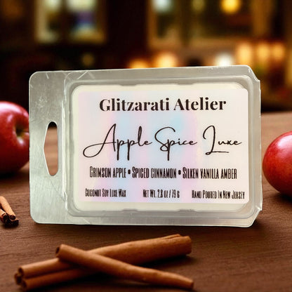 Wax melt packaging labeled 'Glitzerati Atelier Apple Spice Luxe' with apples and cinnamon sticks on a wooden surface.