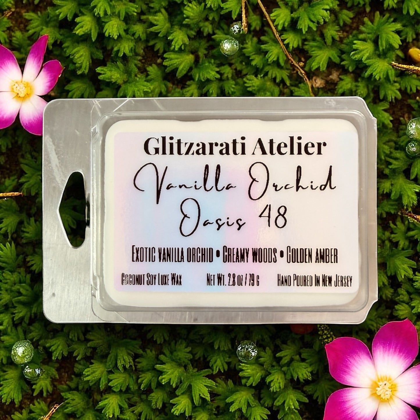 Wax melt package labeled 'Vanilla Orchid Oasis 48' by Glitzerati Atelier on a green leaf background with flowers.