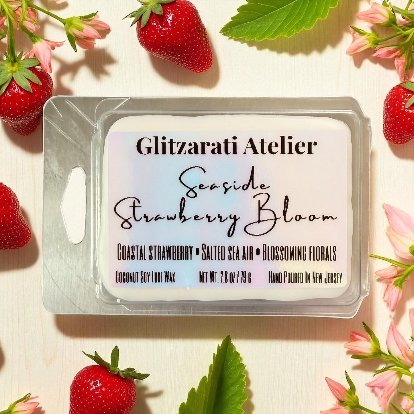 Wax melt packaging with 'Glitzerati Atelier' branding surrounded by strawberries and flowers.