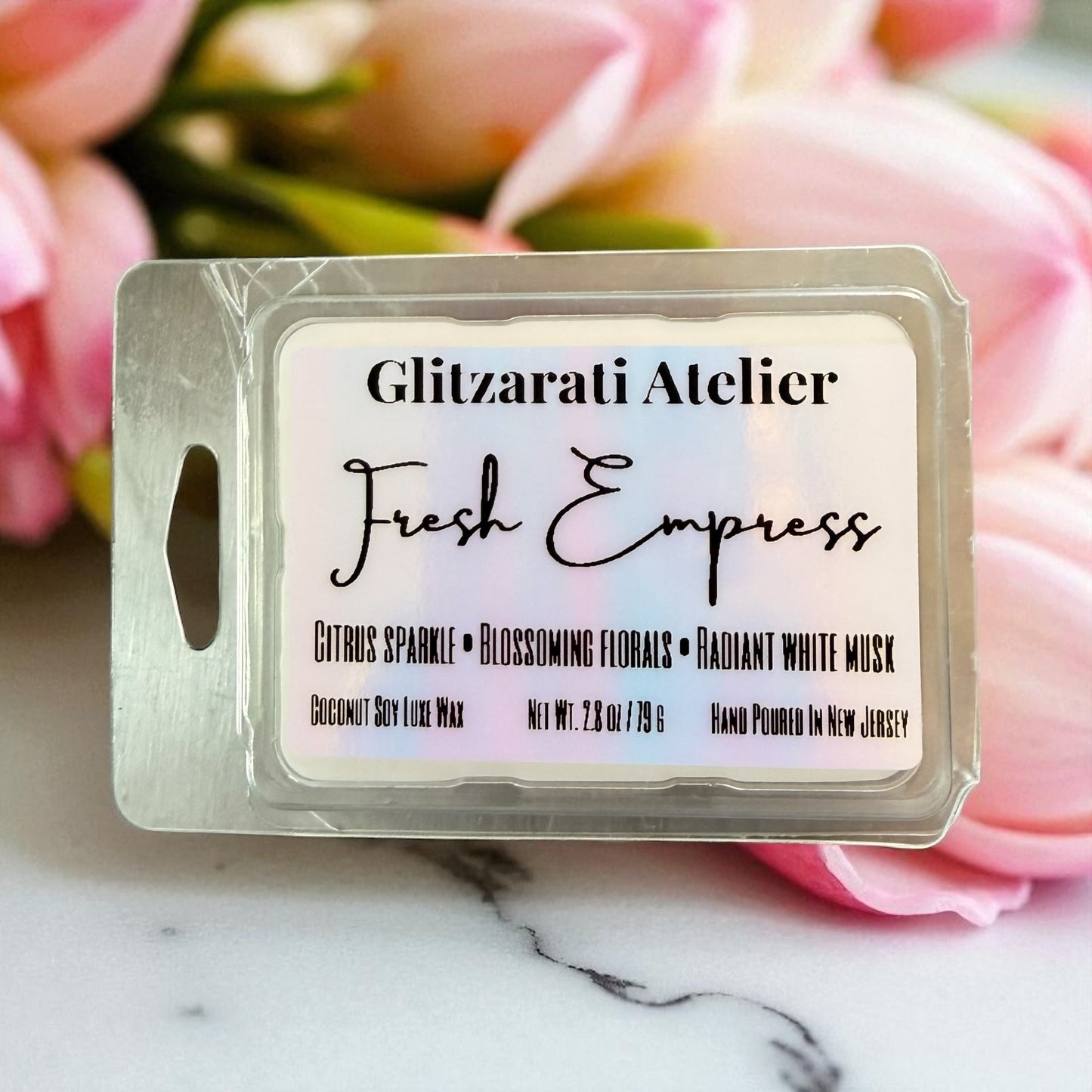 Wax melt package labeled 'Fresh Empress' by Glitzarati Atelier with pink flowers in the background.