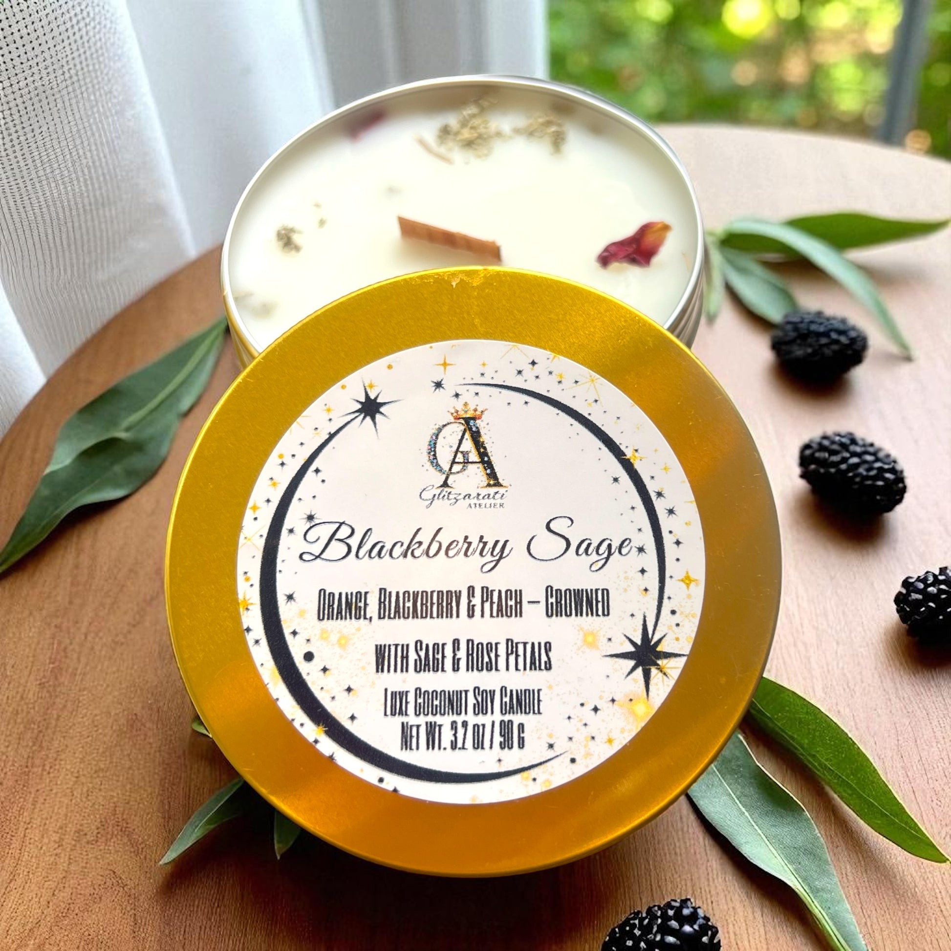 Candle with 'Blackberry Sage' label on a wooden surface with leaves and blackberries.